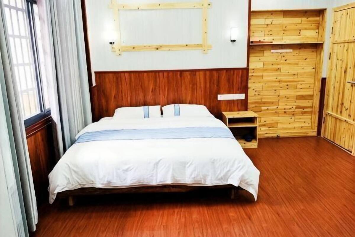Une chambre avec un lit en bois, une petite table de chevet et une armoire en bois.