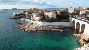 A coastal town with a prominent white bridge and buildings with red-tiled roofs.
