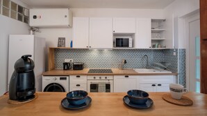 A modern kitchen with white cabinets, a microwave, a coffee maker, a sink, and a dining area with two blue bowls and a white mug.