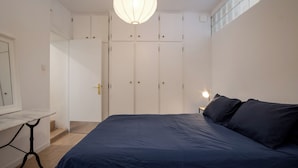 A bedroom with a bed, a desk, and a wardrobe.