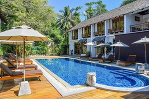 A pool area with lounge chairs and umbrellas, surrounded by a building with multiple balconies. - Sairee Cottage Resort (Koh Tao)