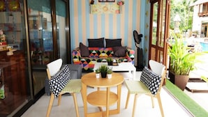Ein Zimmer mit einer gestreiften Wand, einem farbenfrohen Sofa, einem runden Tisch und Stühlen.