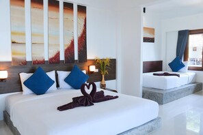 A modern hotel room with a large bed, two bedside tables, a nightstand, a vase with flowers, and a large mirror. - Sairee Cottage Resort (Koh Tao)
