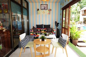 A room with a striped wall, a colorful sofa, a round table, and chairs. - Sairee Cottage Resort (Koh Tao)