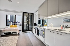 A modern apartment with a bedroom, a kitchen, and a balcony with a city view. - Chic Urban Studio Cloud Nine - 1B1B (Melbourne)