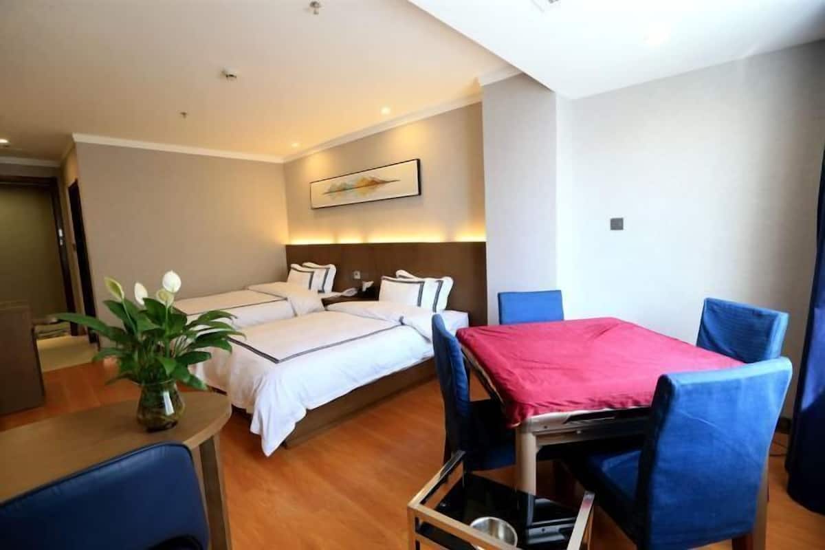 Quarto de hotel com cama, mesa de cabeceira e área de refeições com cadeiras e mesa.