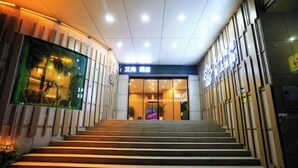 A hotel entrance with a staircase leading to a reception area.