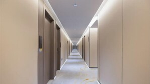 A long, narrow hallway with doors on both sides, leading to individual rooms.