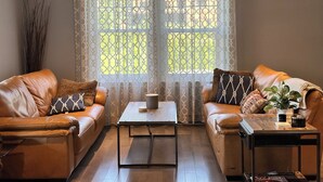 A living room with two leather sofas, a coffee table, and a small side table with a plant. - Melancy waterfront cottage in Sainte-Agathe Nord (Ivry-sur-le-Lac).  (Sainte-Agathe Nord)