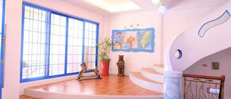 A spacious room with a large window, a staircase, and a wall with a map.