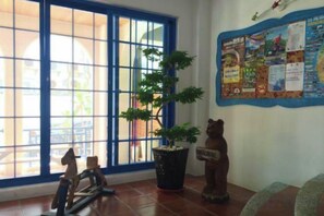 A room with a large window, a bulletin board, a potted plant, and a wooden sculpture.