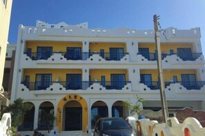 A multi-story building with balconies, a central entrance, and a parked car. - Meet Kenting Hostel (Pingtung)