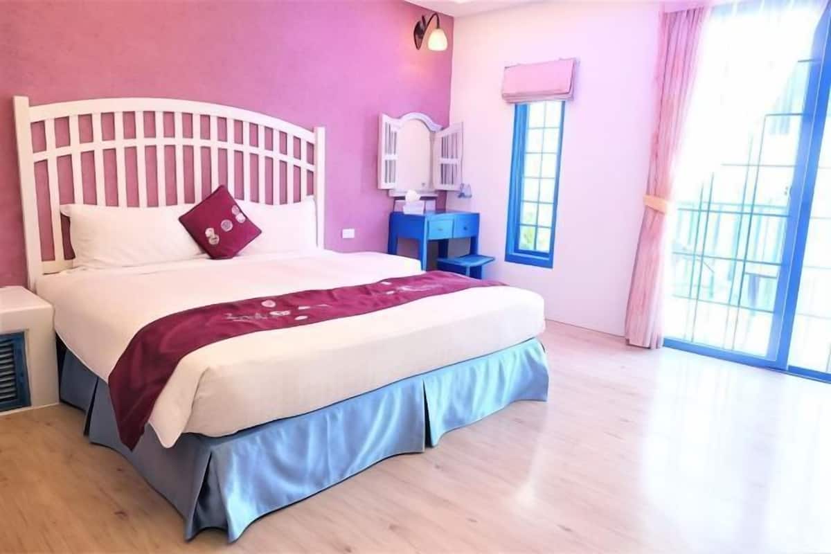 A bedroom with a bed, a nightstand, a dresser, and a window.