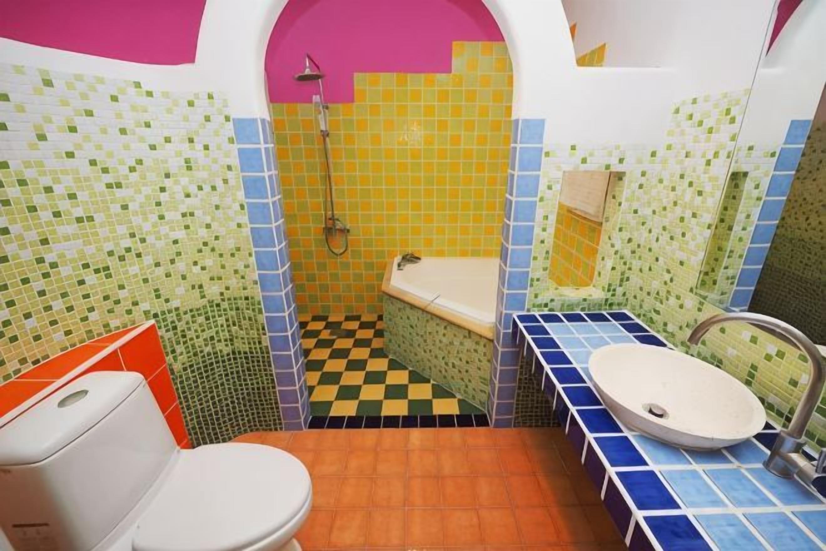 A bathroom with a checkered floor, a toilet, a sink, and a shower.