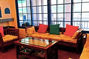 A room with a sofa set, a glass coffee table, and a view through large windows. - Meet Kenting Hostel (Pingtung)