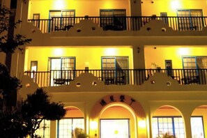 Un hôtel à plusieurs étages, doté de balcons, de fenêtres en arc de cercle et d’une enseigne au-dessus de l’entrée.