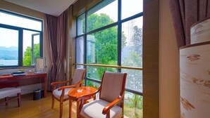 A room with large windows, a desk, two chairs, and a bench.