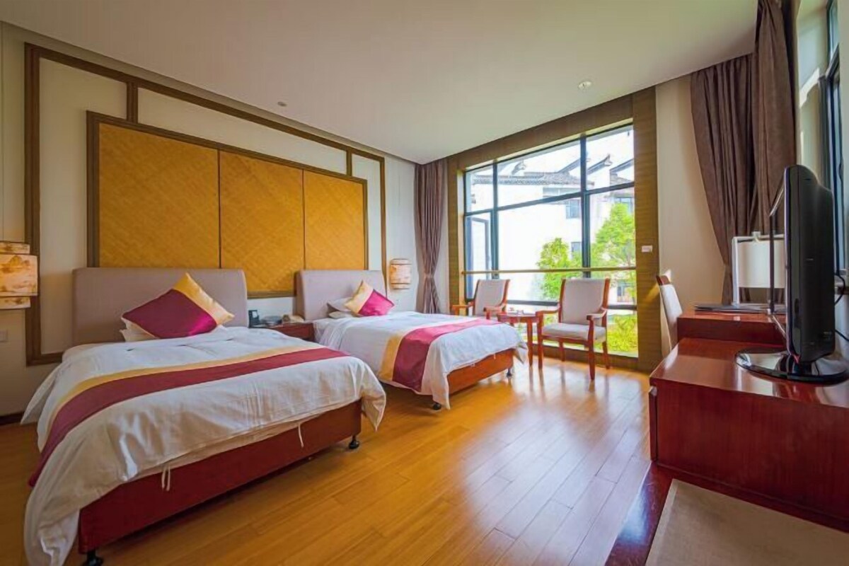 Una habitación de hotel con dos camas, un escritorio, una silla y un televisor.