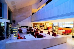 Un espace intérieur vaste et bien aménagé, avec différents types de sièges, notamment des tables et des chaises, ainsi qu’un comptoir d’accueil.