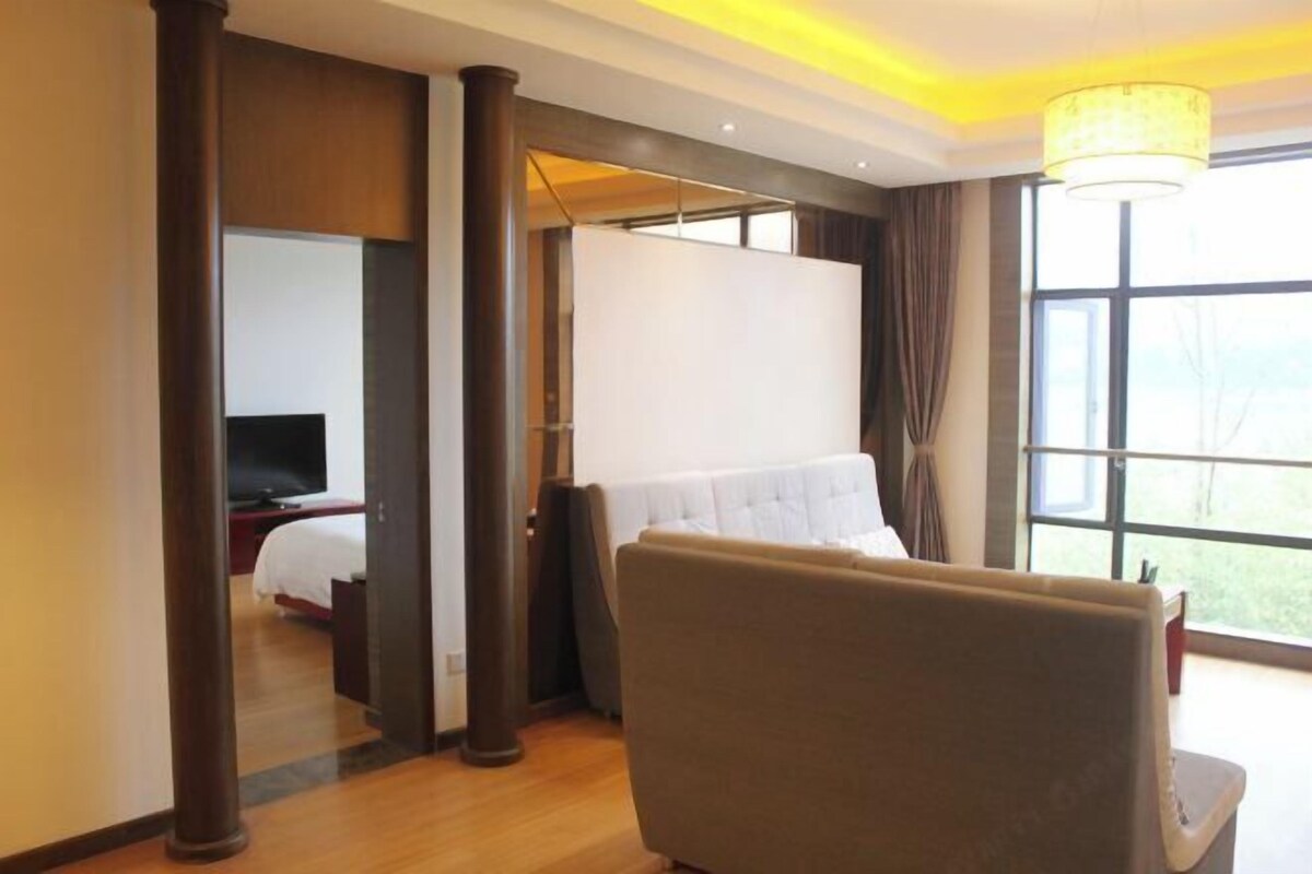 Una habitación de hotel con una cama, una silla, un televisor y un ventanal grande.