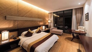 A modern hotel room with a large bed, bedside tables, a desk, and a chair.