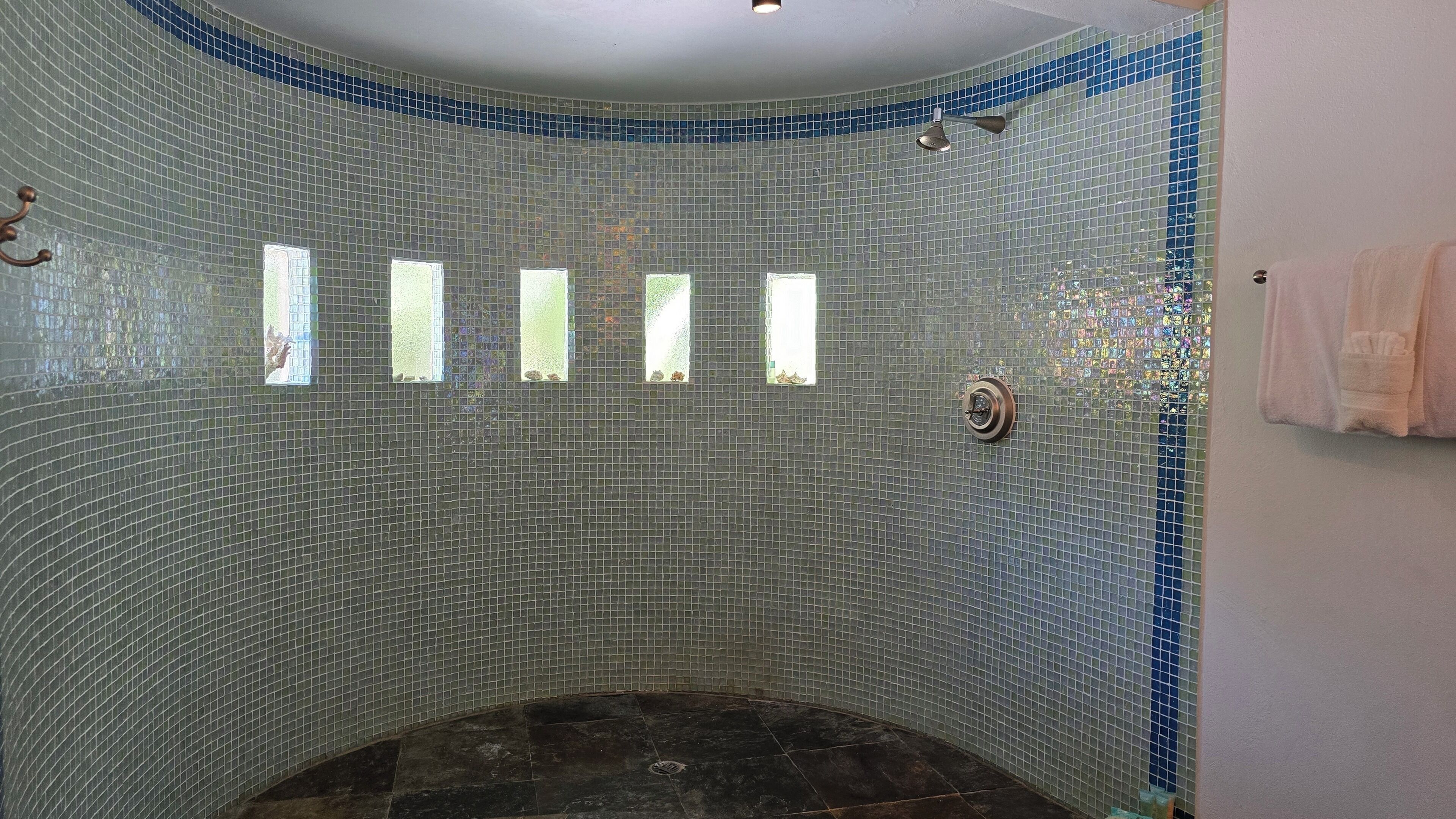 Un bagno con parete curva rivestita di piastrelle, zona doccia e porta asciugamani.