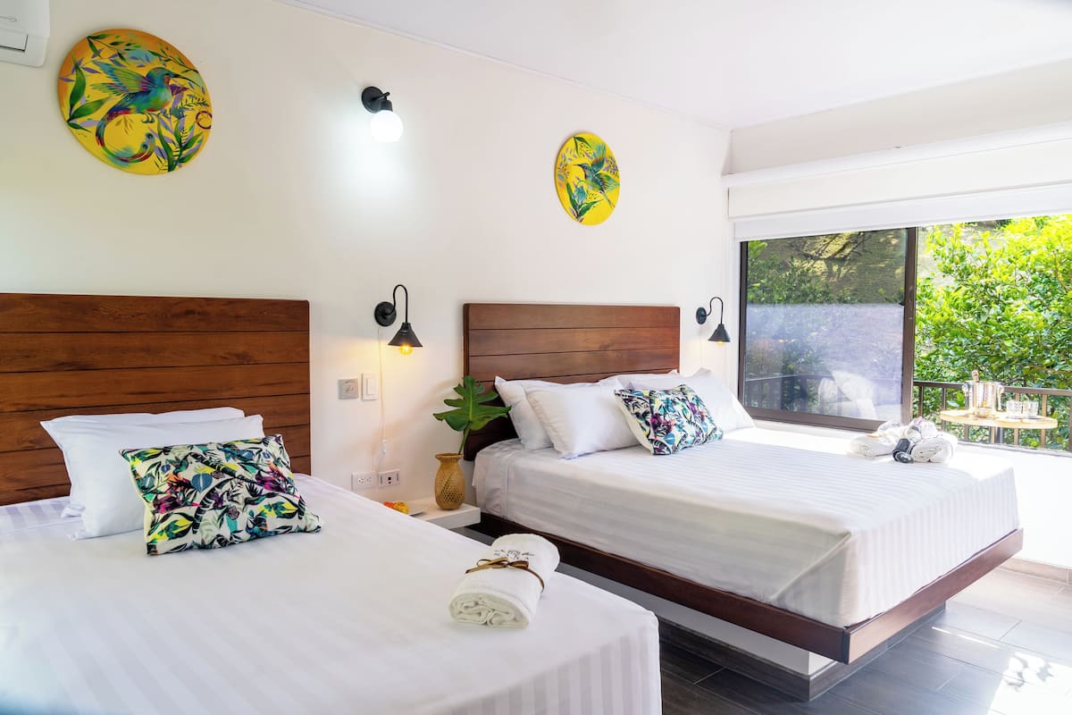 A hotel room with two beds, wooden headboards, white bedding, and artwork on the walls.