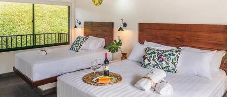 Habitación de hotel con dos camas, balcón y obras de arte en las paredes.