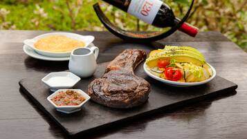 A meal with steak, vegetables, and a bottle of wine on a slate board.
