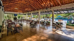 An open-air dining area with wooden ceiling beams and tables and chairs arranged for guests. - Hotel Nana  (Villeta)