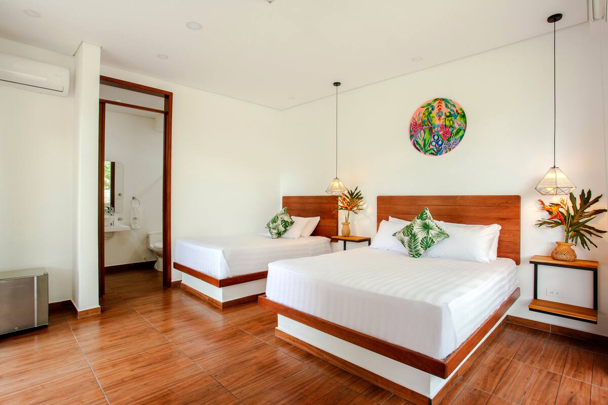 A hotel room with two beds, a wooden headboard, a wall-mounted globe, and a small plant on the nightstand.