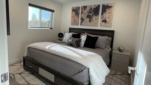 Una camera da letto con un letto, un comodino, una finestra e due mappe appese al muro.