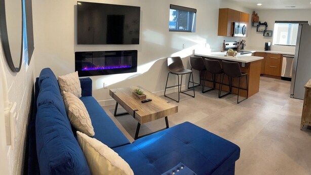 Un soggiorno moderno con un divano blu, un tavolino in legno e una TV a parete.
