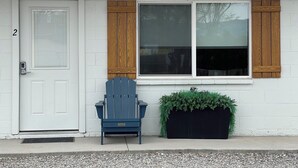 A house with a white door, a blue Adirondack chair, and a black planter with green plants. - Modern, One Bedroom Apartment in Bryce Canyon Country, Panguitch, Utah (Panguitch)