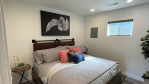 A bedroom with a bed, a window, a painting, and a small table with a plant. - Modern, One Bedroom Apartment in Bryce Canyon Country, Panguitch, Utah (Panguitch)