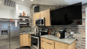 Una cucina moderna con frigorifero in acciaio inox, forno a microonde, forno e macchina del caffè.