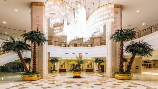 A spacious lobby with a grand chandelier, palm trees, and a central floral arrangement. - Changxing International Hotel (Changxing)