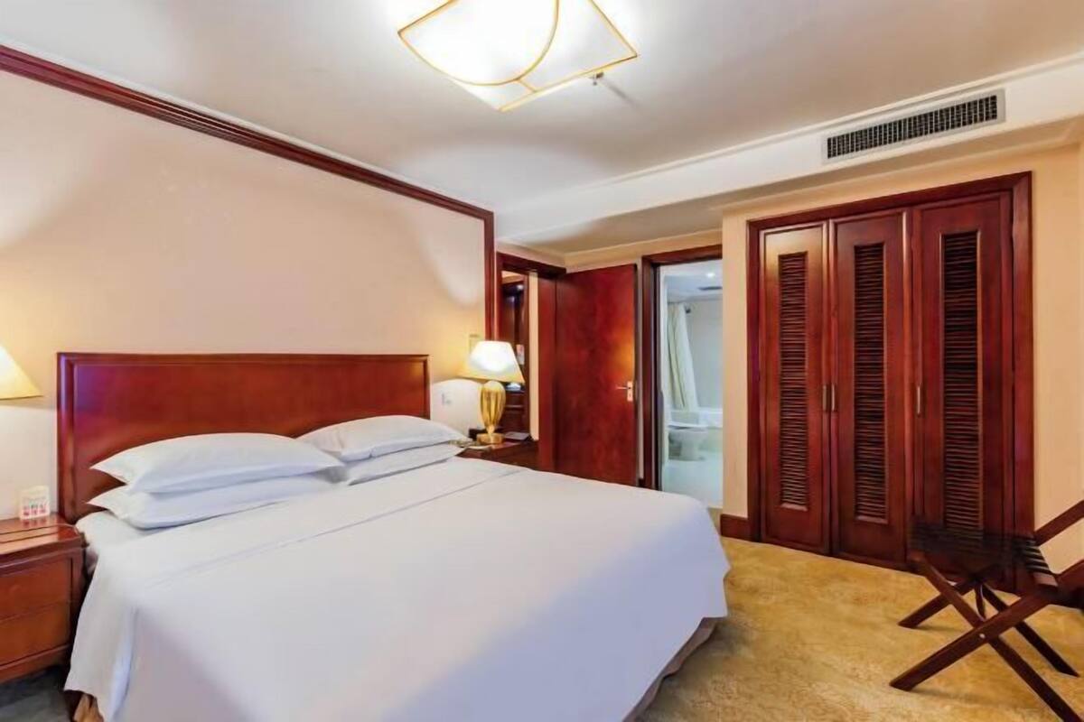 Ein Hotelzimmer mit einem großen Bett, einem Nachttisch, einem Schreibtisch, einem Stuhl und einem Kleiderschrank.