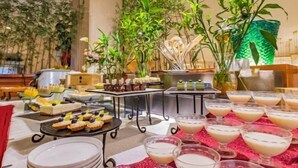 A buffet setup with various food items and beverages, surrounded by indoor plants and a green glass wall. - Changxing International Hotel (Changxing)