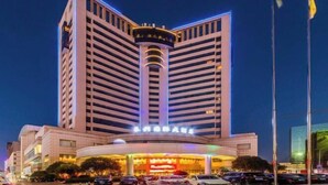 A multi-story hotel with a prominent central tower and a well-lit entrance. - Changxing International Hotel (Changxing)