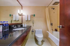 A bathroom with a toilet, sink, and bathtub. There are towels hanging on the wall and a phone mounted on the wall.