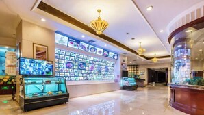 A hotel lobby with a large display wall of photos, a reception desk, and a glass display case with items. - Changxing International Hotel (Changxing)