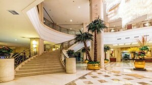 A spacious lobby with a marble floor, a grand staircase, and decorative plants. - Changxing International Hotel (Changxing)