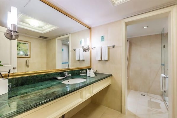 A hotel bathroom with a large mirror, a sink, and a shower.