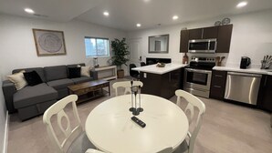 A modern kitchen with a central island, a dining area with a round table, and a living area with a sofa and a coffee table. - Modern, One Bedroom Pet Friendly Apartment in Bryce Canyon Country, Panguitch, Utah (Panguitch)