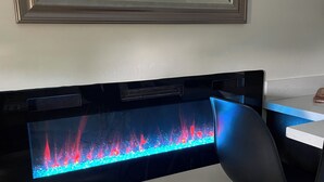 A modern room with a long, narrow aquarium on the wall, a wooden chair, and a white table. - Modern, One Bedroom Pet Friendly Apartment in Bryce Canyon Country, Panguitch, Utah (Panguitch)