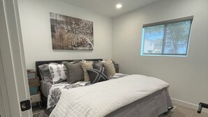 A bedroom with a bed, a nightstand, a wall-mounted artwork, a window, and a carpeted floor. - Modern, One Bedroom Pet Friendly Apartment in Bryce Canyon Country, Panguitch, Utah (Panguitch)