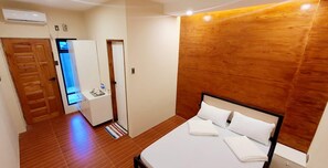 A bedroom with a wooden headboard, a bed with white linens, a small bedside table, and a wooden wardrobe. - Elpise Inn Hostel Alabel (Alabel)