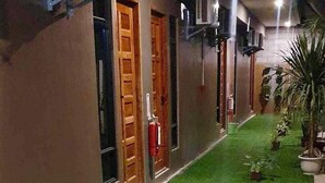 Un pasillo con césped artificial, plantas en macetas y unidades de aire acondicionado montadas en la pared.
