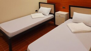 Una habitación de hotel con dos camas individuales, un panel de madera decorativo y suelo de baldosas.